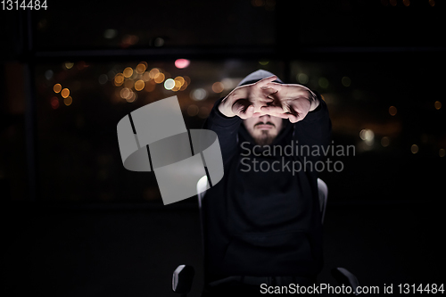 Image of hacker using laptop computer while working in dark office