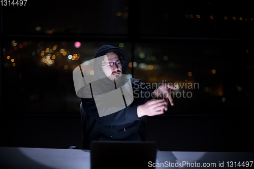 Image of hacker using laptop computer while working in dark office