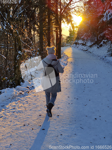 Image of Woman hiking on snow in white winter forest berore the sunset. Recreation and healthy lifestyle outdoors in nature