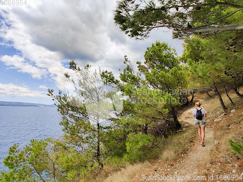 Image of Young active feamle tourist wearing small backpack walking on co