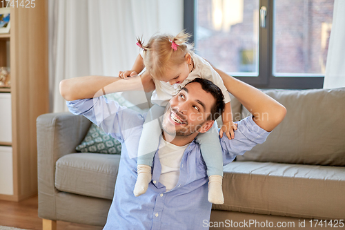 Image of father riding little baby daughter on neck at home