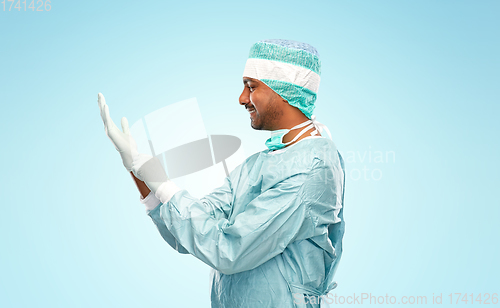 Image of indian male doctor or surgeon putting glove on