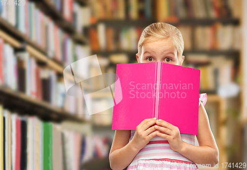 Image of little girl hiding over book at library