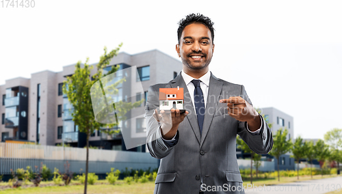 Image of indian man realtor with house model on city street