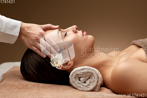 Image of woman having face and head massage at spa