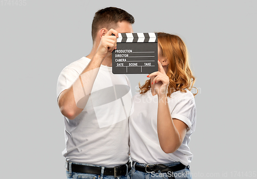 Image of happy couple in white t-shirts with clapperboard