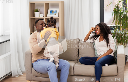 Image of african family playing with baby daughter at home