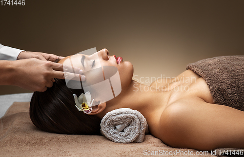 Image of woman having face and head massage at spa