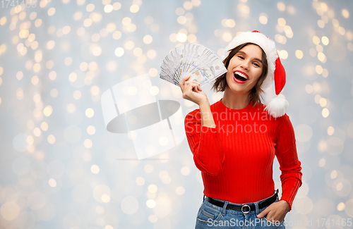 Image of happy woman in santa hat with money on christmas