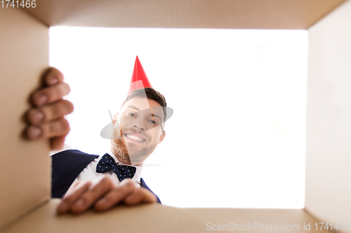 Image of happy young man looking into open birthday gift