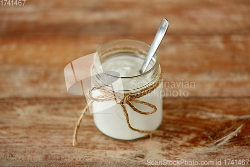 Image of yogurt or sour cream in glass jar on wooden table