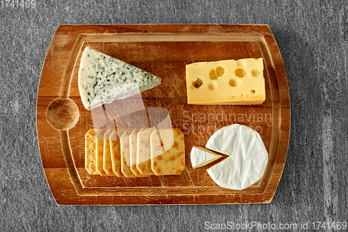 Image of different cheeses and crackers on wooden board