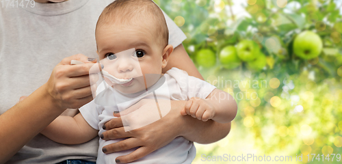 Image of close up of mother with spoon feeding little baby