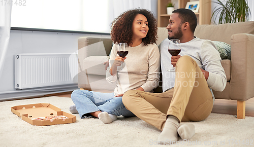 Image of happy couple with wine and takeaway pizza at home