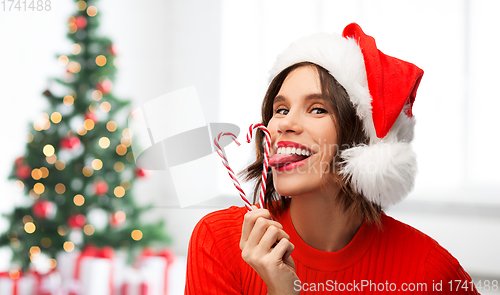 Image of woman in santa hat licks candy canes on christmas