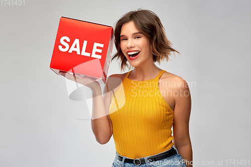 Image of happy smiling young woman posing with sale sign