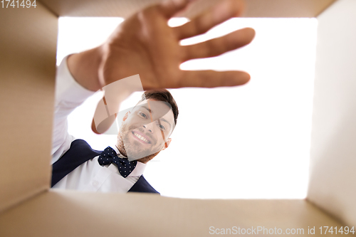 Image of happy young man looking into open gift box