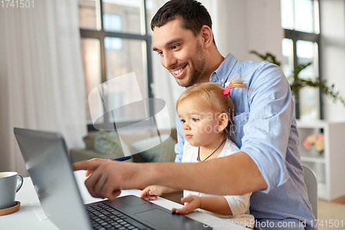 Image of working father with baby daughter at home office