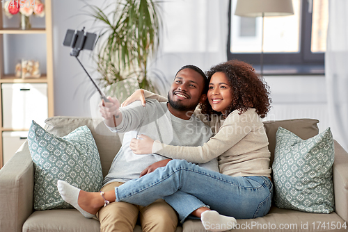 Image of couple taking picture by selfie stick at home