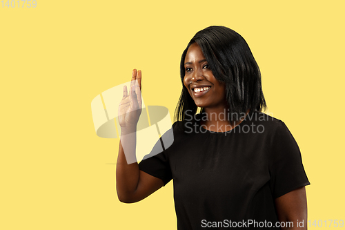 Image of Young african woman isolated on yellow studio background, facial expression