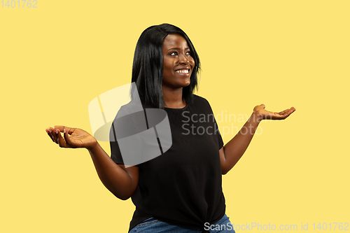 Image of Young african woman isolated on yellow studio background, facial expression