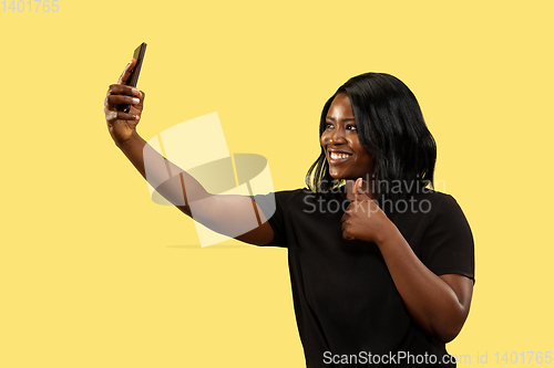 Image of Young african woman isolated on yellow studio background, facial expression