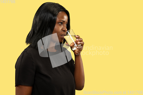 Image of Young african woman isolated on yellow studio background, facial expression