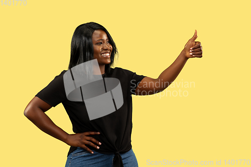 Image of Young african woman isolated on yellow studio background, facial expression