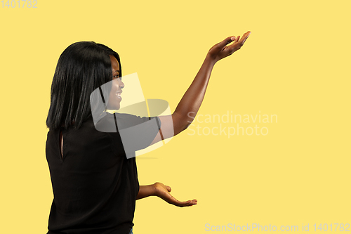 Image of Young african woman isolated on yellow studio background, facial expression