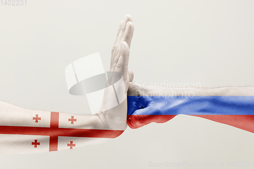 Image of Two hands. Flag of Russian Federation. Flag of Georgia.