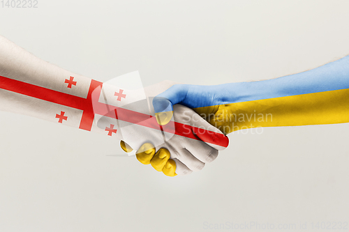 Image of Two hands. Flag of Georgia. Flag of Ukraine.