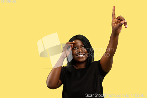 Image of Young african woman isolated on yellow studio background, facial expression