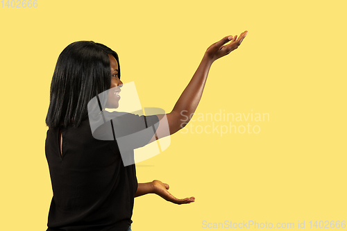 Image of Young african woman isolated on yellow studio background, facial expression