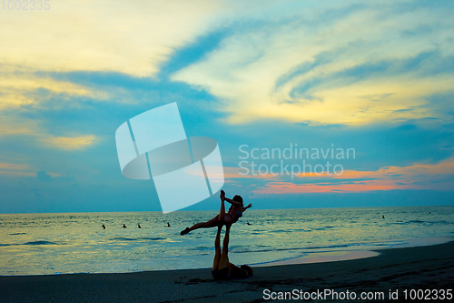 Image of Couple practice yoga at beach 