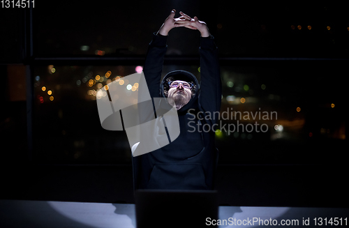 Image of hacker using laptop computer while working in dark office