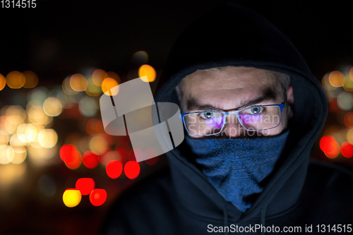 Image of hacker using laptop computer while working in dark office