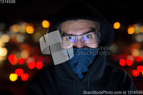 Image of hacker using laptop computer while working in dark office