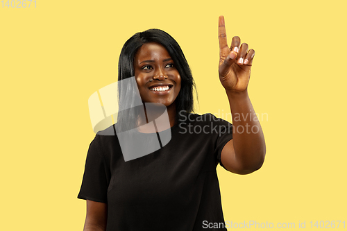 Image of Young african woman isolated on yellow studio background, facial expression