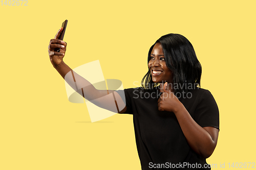 Image of Young african woman isolated on yellow studio background, facial expression