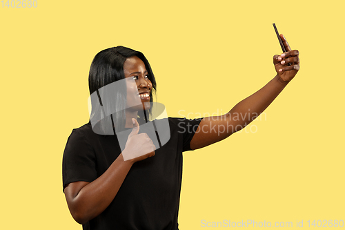 Image of Young african woman isolated on yellow studio background, facial expression