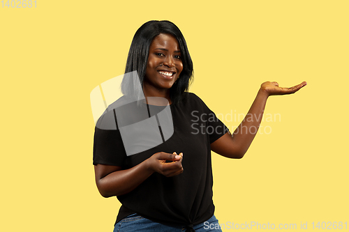 Image of Young african woman isolated on yellow studio background, facial expression