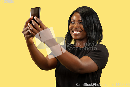 Image of Young african woman isolated on yellow studio background, facial expression