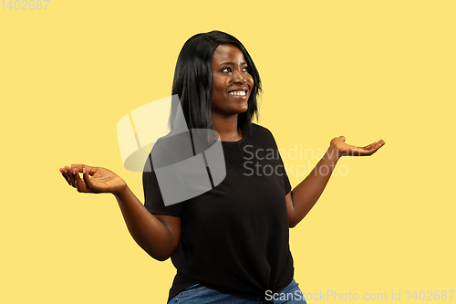 Image of Young african woman isolated on yellow studio background, facial expression