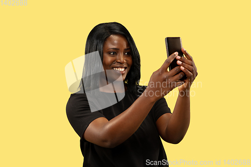 Image of Young african woman isolated on yellow studio background, facial expression