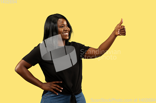 Image of Young african woman isolated on yellow studio background, facial expression