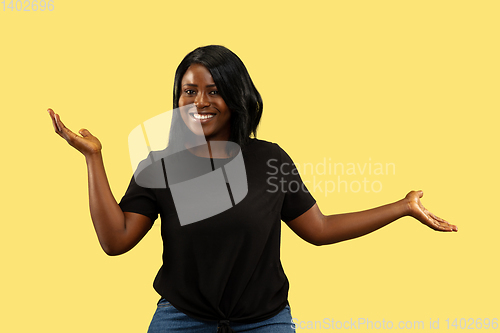 Image of Young african woman isolated on yellow studio background, facial expression