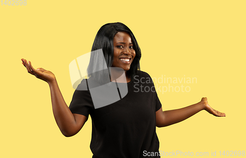 Image of Young african woman isolated on yellow studio background, facial expression