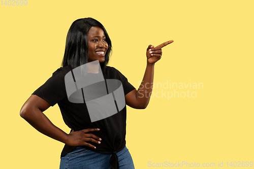 Image of Young african woman isolated on yellow studio background, facial expression