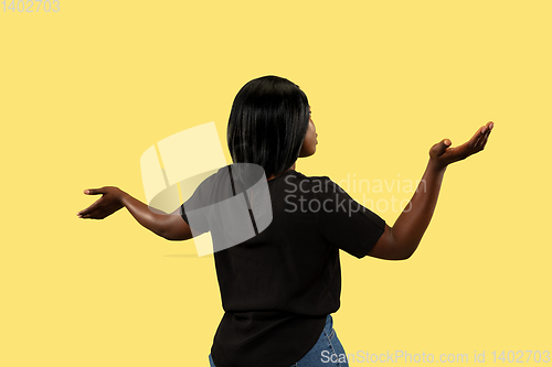 Image of Young african woman isolated on yellow studio background, facial expression