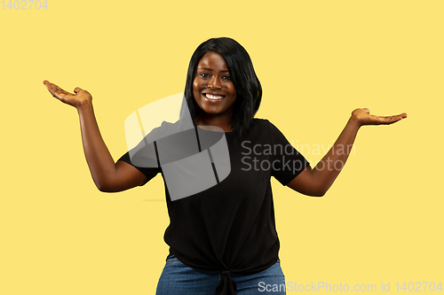 Image of Young african woman isolated on yellow studio background, facial expression